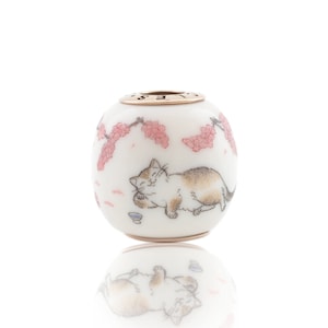 Peut inclure: Perle en céramique blanche avec un dessus en métal doré. La perle présente un motif peint à la main d'un chat dormant sous un cerisier en fleurs.