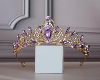May include: A gold tiara with purple and clear rhinestones. The tiara has a pointed crown and a delicate design.