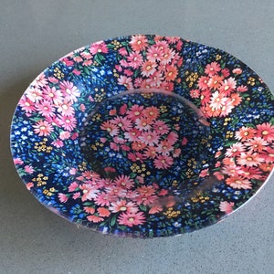 May include: A blue and white floral patterned ceramic bowl with pink flowers. The bowl is round and has a slightly raised rim.