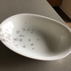 May include: White oval serving bowl with a delicate floral pattern in gold. The bowl is perfect for serving salads, fruit, or snacks.