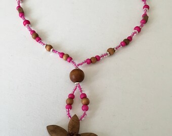 Pink beaded necklace with a wooden flower pendant