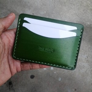 Puede incluir: Un porta tarjetas de cuero verde con costuras blancas y el texto "The Works" en relieve en la parte delantera.