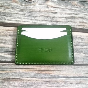 Puede incluir: Un porta tarjetas de cuero verde con un borde cosido y el texto "Tree Works" en relieve en la parte delantera.