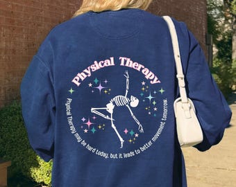 May include: Navy blue sweatshirt with a circular graphic that reads "Physical Therapy" and features a skeleton in a yoga pose. The text "Physical Therapy may be hard today, but it leads to better movement tomorrow" is also printed on the sweatshirt.