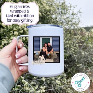 Puede incluir: Taza de viaje blanca con asa, con una foto enmarcada de una pareja y un perro. La taza tiene un borde plateado y el texto "The Whites" debajo de la foto. La taza es sostenida por una persona.