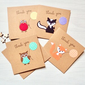 May include: Four brown thank you cards with different animal illustrations. Each card features an animal holding a balloon with polka dots. The animals are a robin, a skunk, an owl, and a fox.