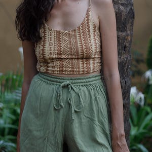 Könnte beinhalten: Eine Frau trägt ein zweiteiliges Outfit. Das Oberteil ist ein beiges Crop-Top mit einem braunen geometrischen Muster. Die Shorts sind hellgrün mit einem Kordelzug in der Taille. Das Outfit ist lässig und sommerlich.