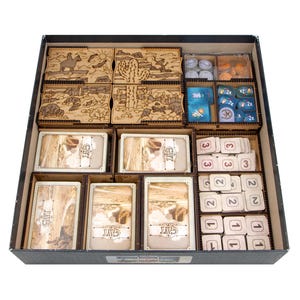 Könnte beinhalten: Ein Holz-Brettspiel-Organizer mit mehreren Fächern. Der Organizer enthält Holzkisten mit eingravierten Wüstenszenen, Karten und verschiedenen Spielsteinen. Die Karten tragen die Buchstaben "GWT". Der Organizer befindet sich in einer schwarzen Box.