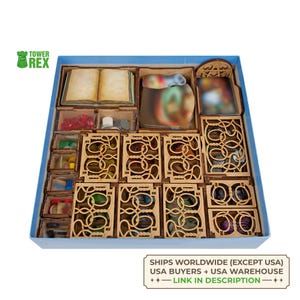 Puede incluir: Una caja azul que contiene organizadores y componentes de juego de madera. La caja incluye compartimentos para cartas, fichas y otras piezas del juego. Los organizadores son de madera clara con intrincados diseños recortados. También se incluye el texto "SHIPS WORLDWIDE (EXCEPT USA)".