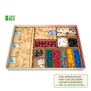 May include: A wooden board game organizer with various compartments filled with game pieces. The organizer features laser-cut floral designs and contains dice, red, green, gray, yellow, and blue game pieces. The text "TOWER REX" is visible.