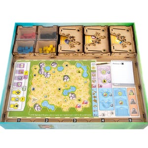 May include: A wooden board game organizer insert inside a box, featuring four small square containers holding red, black, blue, and yellow cubes, three rectangular card holders with gold-colored metal clips, and a game board with a hexagonal map.