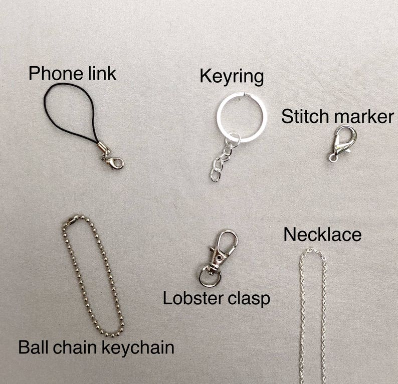May include: Assortment of silver-toned metal clasps and chains, including a phone link, keyring, stitch marker, ball chain keychain, lobster clasp, and necklace.