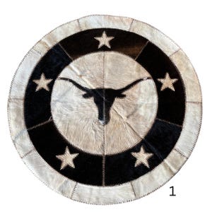 May include: Round cowhide rug with a Texas Longhorn silhouette in the center. The rug features a black and white star and stripe design. The number "1" is in the bottom right corner.