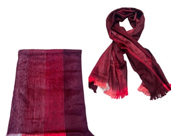 May include: A rectangular scarf featuring a gradient of deep burgundy, maroon, and bright red tones with a fringed edge, displayed both folded in a flat, vertical orientation and draped in a loose, knotted loop to show the texture and color.