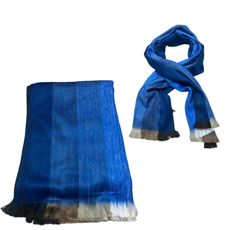 May include: A rectangular blue scarf with a subtle vertical striped pattern and a fringed edge featuring gradient tones of black, gray, and white. The scarf is displayed in two ways: one folded flat and one tied in a loose loop to show the texture.