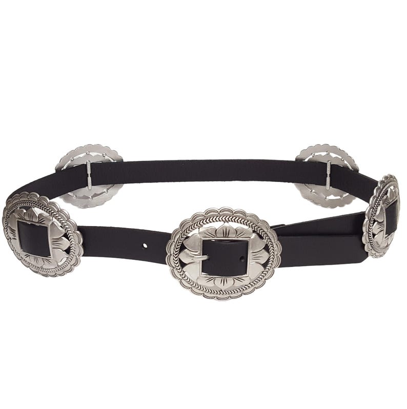 May include: Black belt with multiple silver-colored decorative buckles. The buckles have a floral design around a square center. The belt is made of a black material and has a classic western style.
