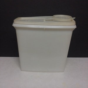 May include: A white plastic cereal dispenser with a lid. The dispenser is tall and rectangular.