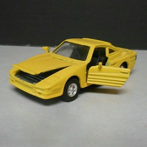 May include: A yellow toy car with a door open. The car has a black grill and black wheels.