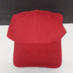 May include: A solid red baseball cap with a curved brim. The cap is made of a soft, cotton fabric.