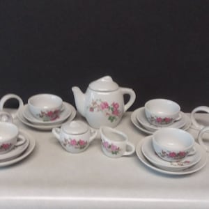 May include: A white porcelain tea set with pink floral designs. The set includes a teapot, creamer, sugar bowl, and four teacups and saucers.