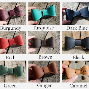 May include: Nine leather bow ties in a variety of colours, including burgundy, turquoise, dark blue, red, brown, black, green, ginger, and caramel. Some bow ties have names on them, such as "Beta" and "Lucae".