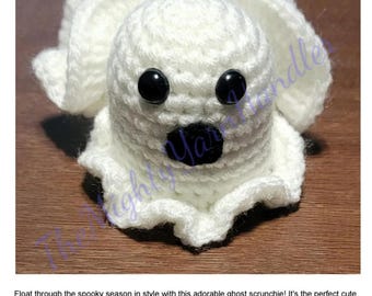 Può includere: Un fermacoda a forma di fantasma all'uncinetto bianco fatto a mano con occhi a bottone neri e una bocca nera. L'accessorio per capelli è a tema Halloween. Il testo "Ghost Scrunchie Crochet Pattern" è in alto.