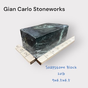 Peut inclure: Bloc de stéatite vert foncé de Gian Carlo Stoneworks. Le bloc pèse 9,07 kg et mesure environ 22,86x11,43x11,43 cm. La surface a un aspect marbré avec des veines de couleur claire. Le texte "Soapstone Block" est visible.