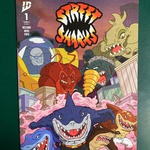 May include: Comic book cover featuring the title "Street Sharks" in orange and white. The artwork depicts several anthropomorphic sharks in action, with a cityscape and pink clouds in the background. The comic book is labeled "1".