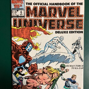 May include: Comic book cover for "The Official Handbook of the Marvel Universe" Deluxe Edition. Features various Marvel characters in action, including Human Torch and Ka-Zar. The cover has a white background with the Marvel logo and issue details.