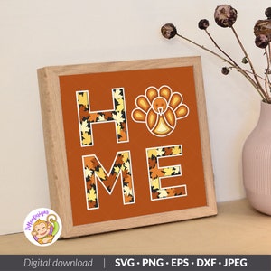 May include: A framed sign with the word "HOME" spelled out in large letters. The letters are filled with a pattern of autumn leaves in shades of orange, yellow, and brown. A stylized turkey is centered above the word "HOME".