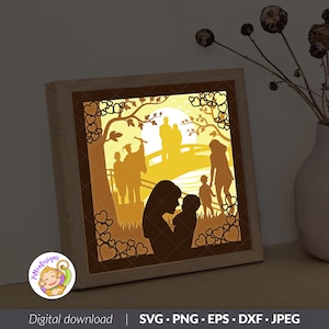 Könnte beinhalten: Eine digitale Schnittdatei mit der Silhouette einer Familie, bestehend aus einer Mutter, die ein Baby hält, einem Vater und zwei Kindern, die auf einer Brücke stehen, sowie einem Absolventen mit Mütze und Robe. Das Design ist von Herzen und einem Baum umgeben. Das Design eignet sich perfekt für die Erstellung einer Schattenbox oder eines beleuchteten Schildes.