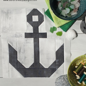 Peut inclure: Un bloc de courtepointe d'ancre noir et blanc avec un fond blanc et une ancre noire. L'ancre est composée de plusieurs carrés et triangles. Le bloc de courtepointe est sur une surface blanche.