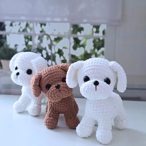 May include: Three crocheted stuffed dog toys. One is white, one is brown, and one is white with black eyes.