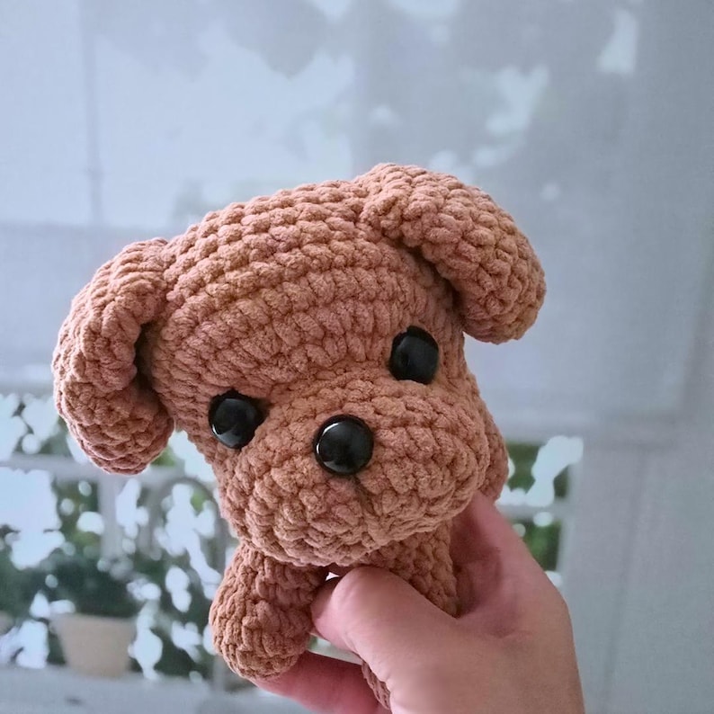 May include: A brown crocheted stuffed dog toy with black button eyes.