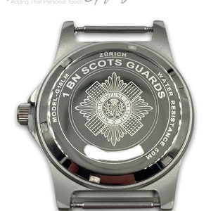 Puede incluir: Un reloj de pulsera plateado con una esfera negra y una correa plateada. La esfera del reloj tiene las palabras "1 BN SCOTS GUARDS" y "Z&Uuml;RICH" grabadas. El reloj es resistente al agua hasta 50 metros.
