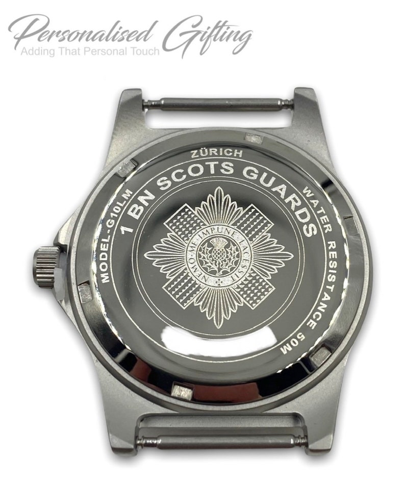 Puede incluir: Un reloj de pulsera plateado con una esfera negra y una correa plateada. La esfera del reloj tiene las palabras "1 BN SCOTS GUARDS" y "Z&Uuml;RICH" grabadas. El reloj es resistente al agua hasta 50 metros.
