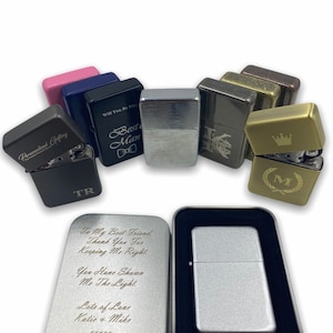 Może przedstawiać: Różne spersonalizowane zapalniczki w różnych kolorach i wykończeniach, w tym srebrne, złote, czarne i niebieskie. Niektóre zapalniczki mają wygrawerowane wiadomości, takie jak "Best Man" i "Will You Be My..."  Inne mają wygrawerowane inicjały i koronę. Zapalniczki są prezentowane w oryginalnym opakowaniu.