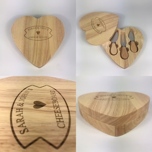 Könnte beinhalten: Ein herzförmiges Käseboard aus Holz mit Deckel und drei kleinen Käsemessern. Das Käseboard ist mit dem Text "Sarah & John's Cheeseboard" und einem kleinen Herz graviert.