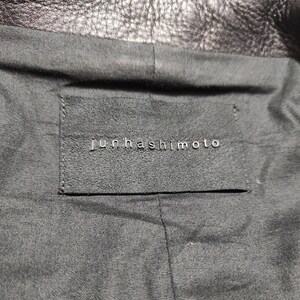 May include: A black leather label with the text "Junhashimoto" in white lettering.
