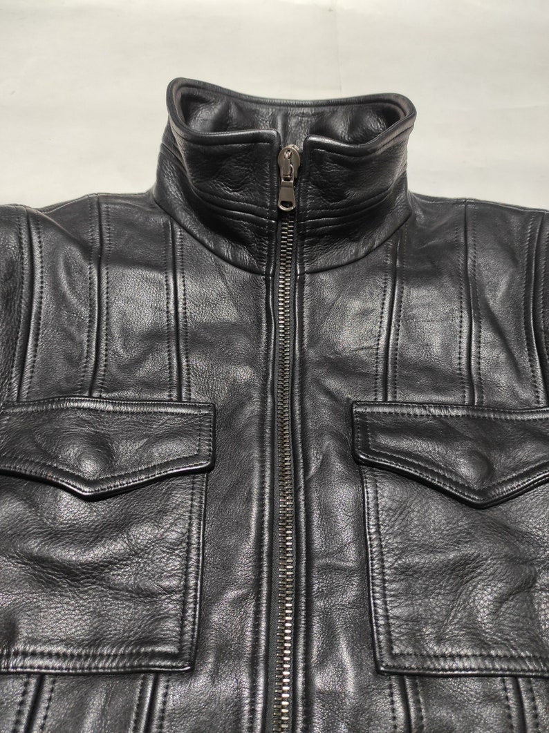 May include: A black leather jacket with a zipper closure and two large flap pockets on the front.