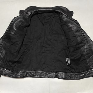 May include: Black leather jacket with a zipper closure and a stand-up collar. The jacket is unlined and has a smooth, soft texture.