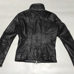 May include: Black leather jacket with a zipper closure and a stand-up collar. The jacket has vertical stitching details on the front and back.