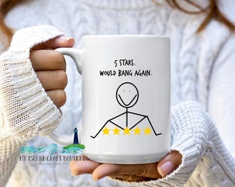 May include: White ceramic mug with the text "5 STARS. WOULD BANG AGAIN." in black. The mug features a stick figure with five gold stars below. The mug is held by a person wearing a white sweater.