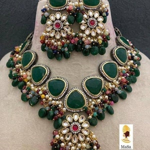 Peut inclure: Un ensemble de collier et de boucles d'oreilles vert et or avec un motif floral et des pierres vertes. Le collier a un grand pendentif avec un motif floral et des pierres vertes. Les boucles d'oreilles sont petites et ont un motif floral avec des pierres vertes.