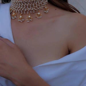 Puede incluir: Un collar gargantilla de oro con m&uacute;ltiples hileras de peque&ntilde;as perlas blancas y colgantes de perlas y pedrer&iacute;a.
