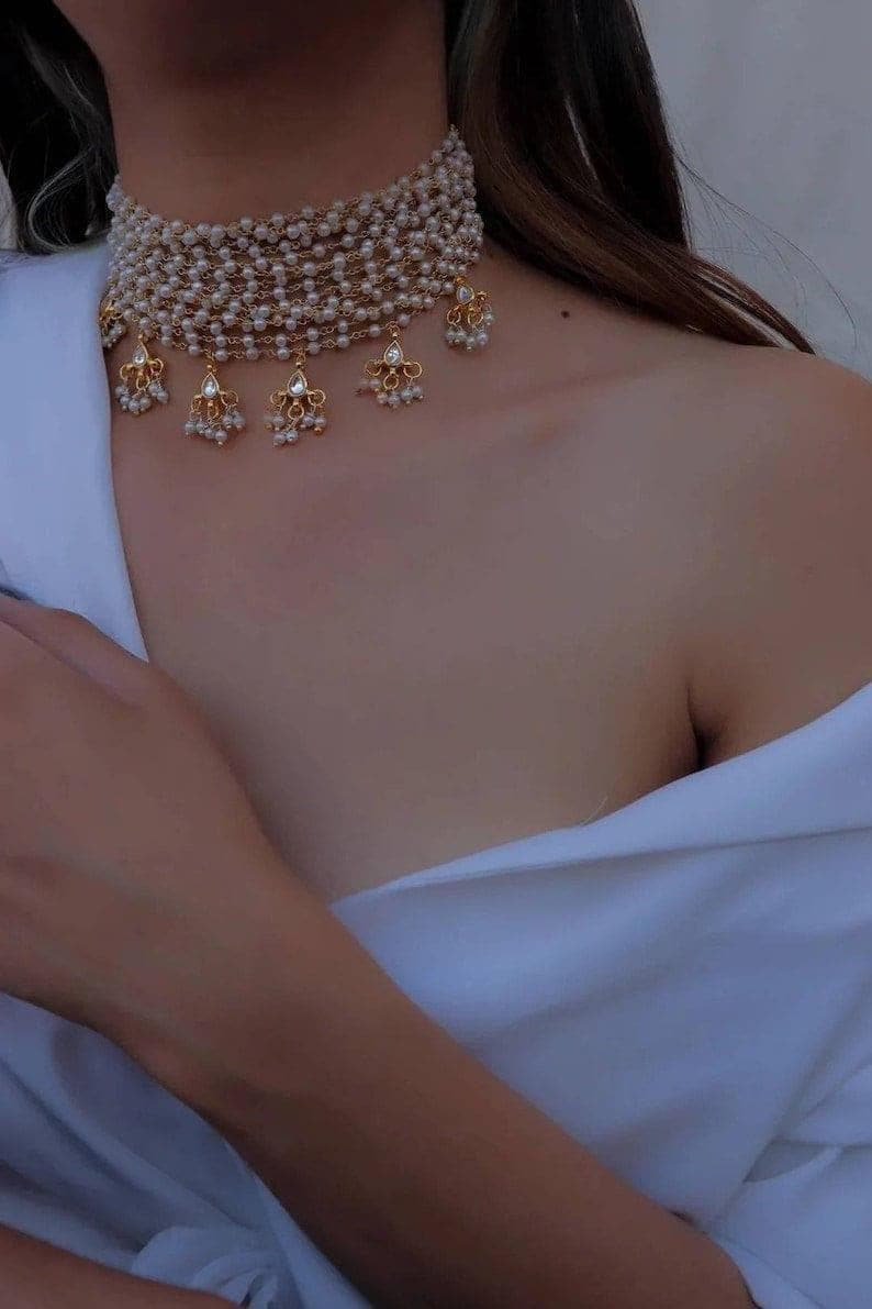 Puede incluir: Un collar gargantilla de oro con m&uacute;ltiples hileras de peque&ntilde;as perlas blancas y colgantes de perlas y pedrer&iacute;a.