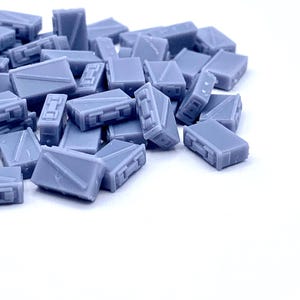 May include: A pile of small, light blue, rectangular boxes. The boxes are made of plastic and have a smooth, matte finish.