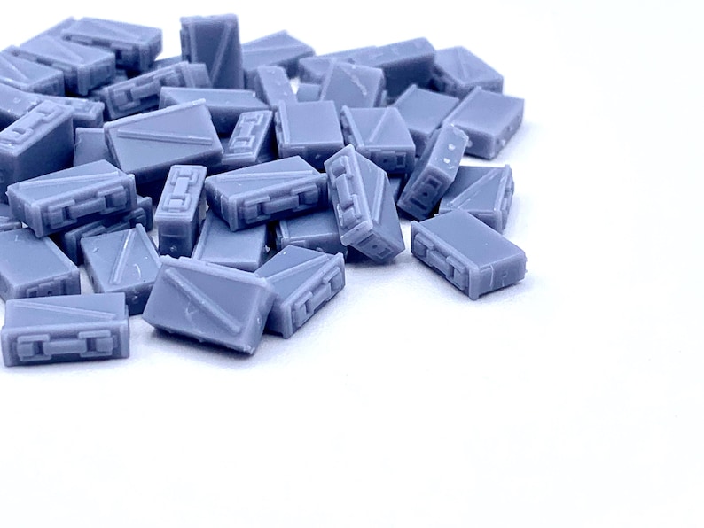 May include: A pile of small, light blue, rectangular boxes. The boxes are made of plastic and have a smooth, matte finish.