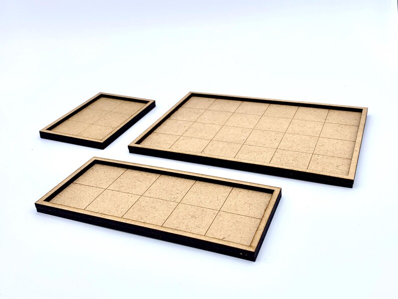 May include: Three wooden game board trays with grid patterns. The trays are rectangular with dark brown edges and a light brown interior. The sizes vary, with one small, one medium, and one large tray.