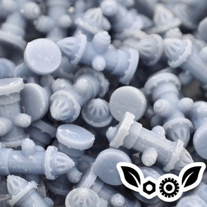 Op de afbeelding: Een close-up van een stapel kleine, grijze, plastic brandkraan-figuurtjes. De figuurtjes zijn allemaal even groot en hebben dezelfde vorm, en ze zijn in een willekeurig patroon gerangschikt.